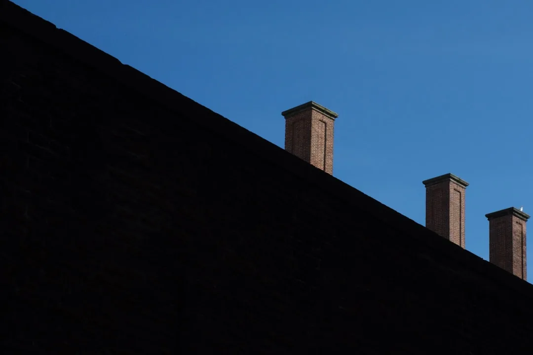 Brick chimneys against a clear blue sky, the calm before roofing storm season begins