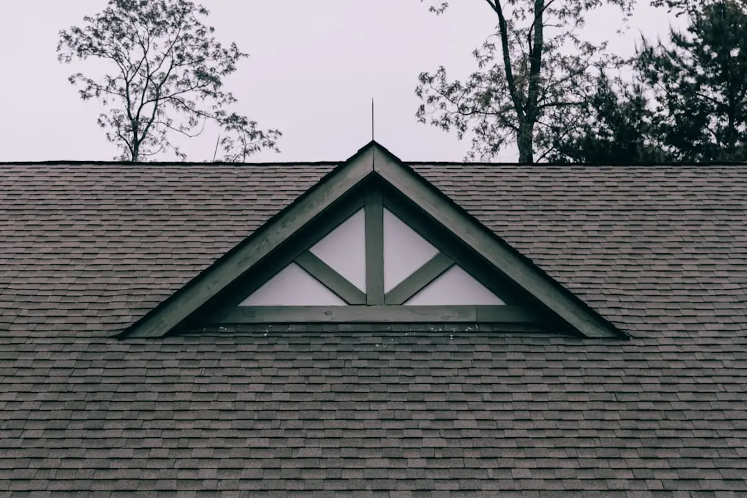 Close-up of a residential roofline with a small triangular window built into the slope