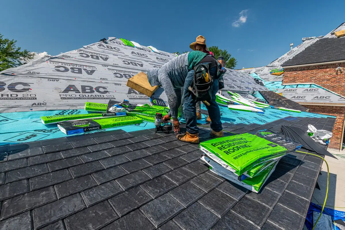 Roofing crew installing a synthetic slate roof on a brick residential home