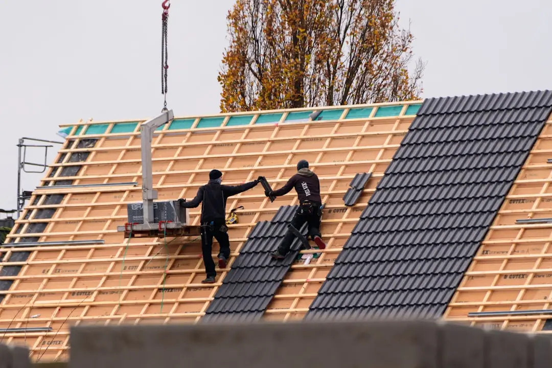 Roofing crew installing tile roofing on a new residential building.