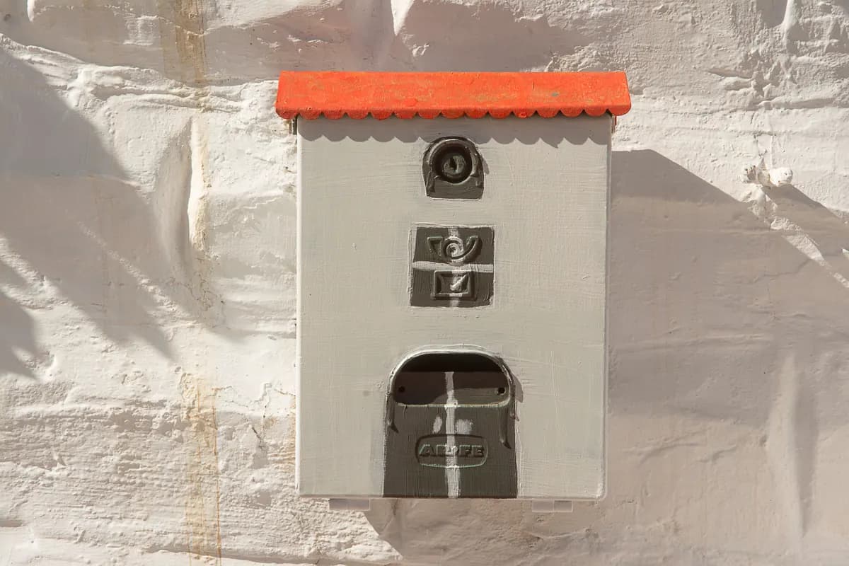 A mailbox with a red roof detail, where a roofing advertising postcard actually lands before it gets read or tossed.