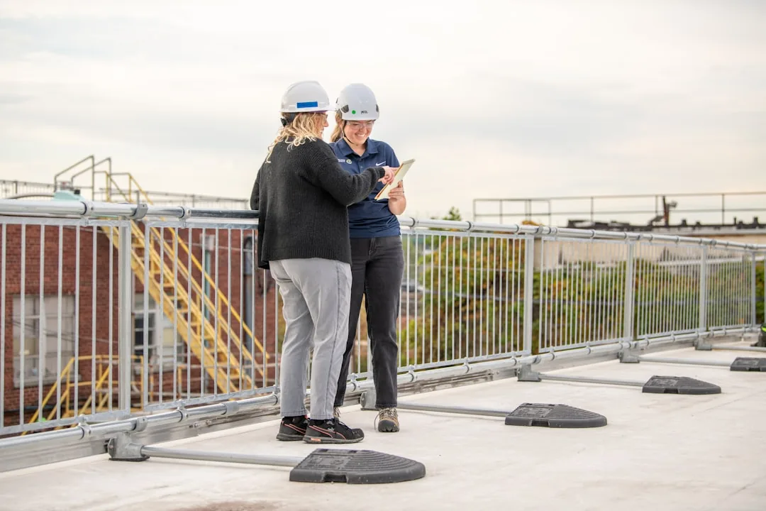 Two roofing contractors reviewing marketing strategy notes together on a rooftop