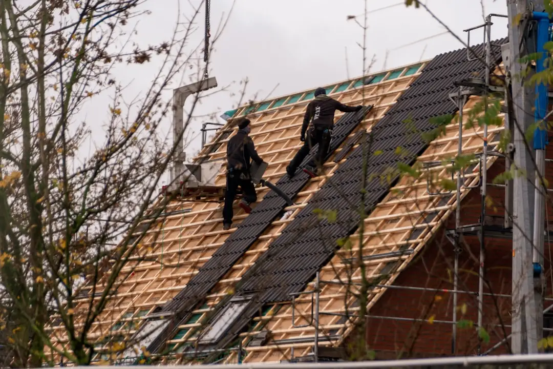 A roofer installs new shingles on a steep residential roof, the kind of job a yard sign advertises to the neighborhood.