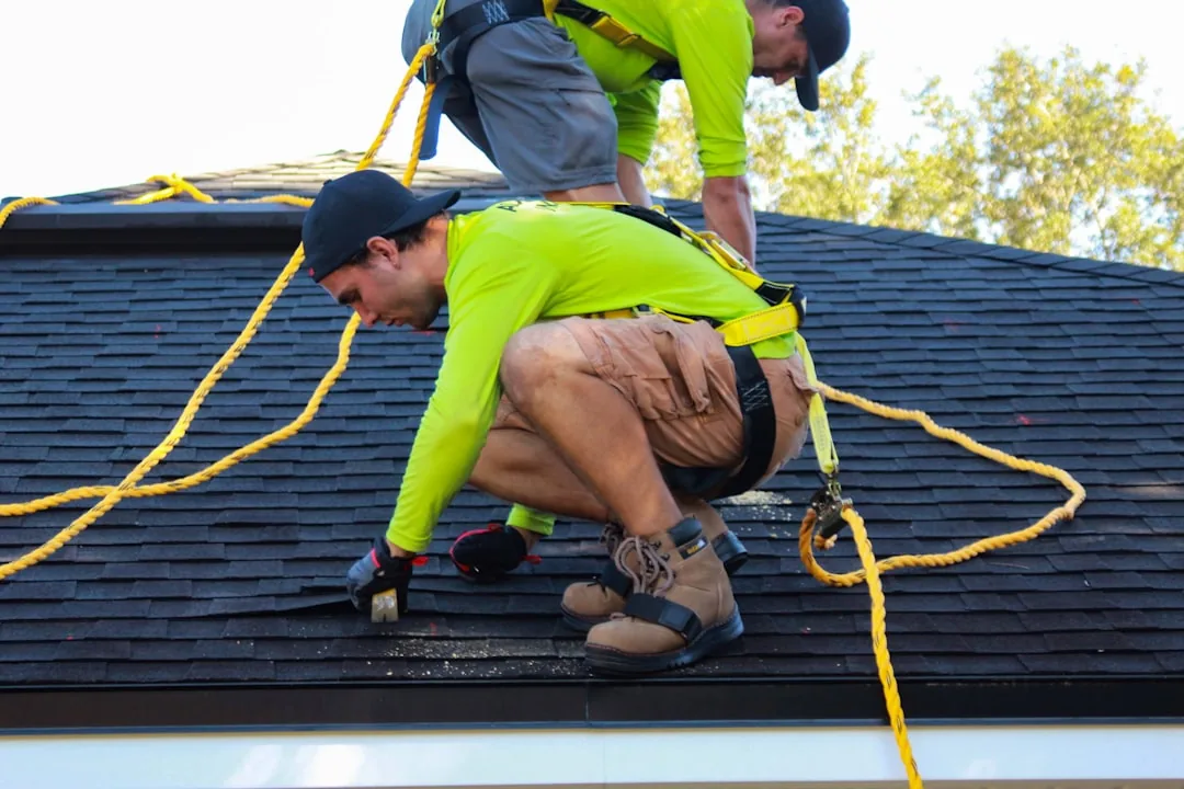 Two roofers working on a residential roof, the real, checkable work behind any SEO result.