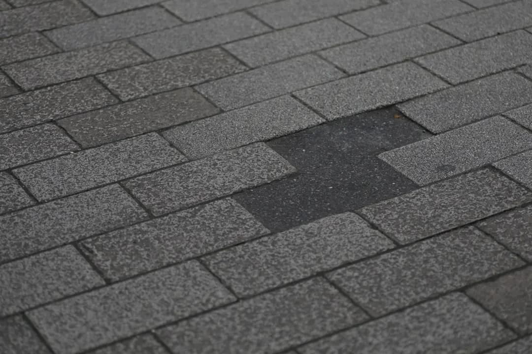 Damaged asphalt shingle roof with shingles torn away, the kind of visible damage that produces an urgent phone call.